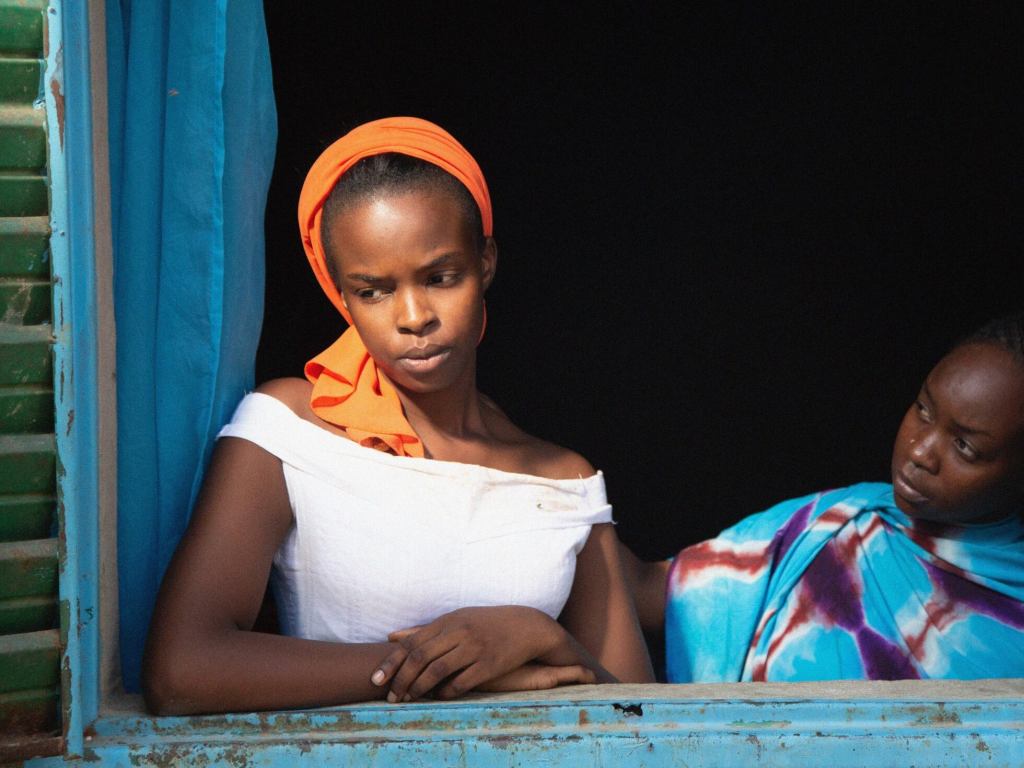 Amina y su hija caminan abrazadas por un camino de tierra en un barrio humilde de Chad.