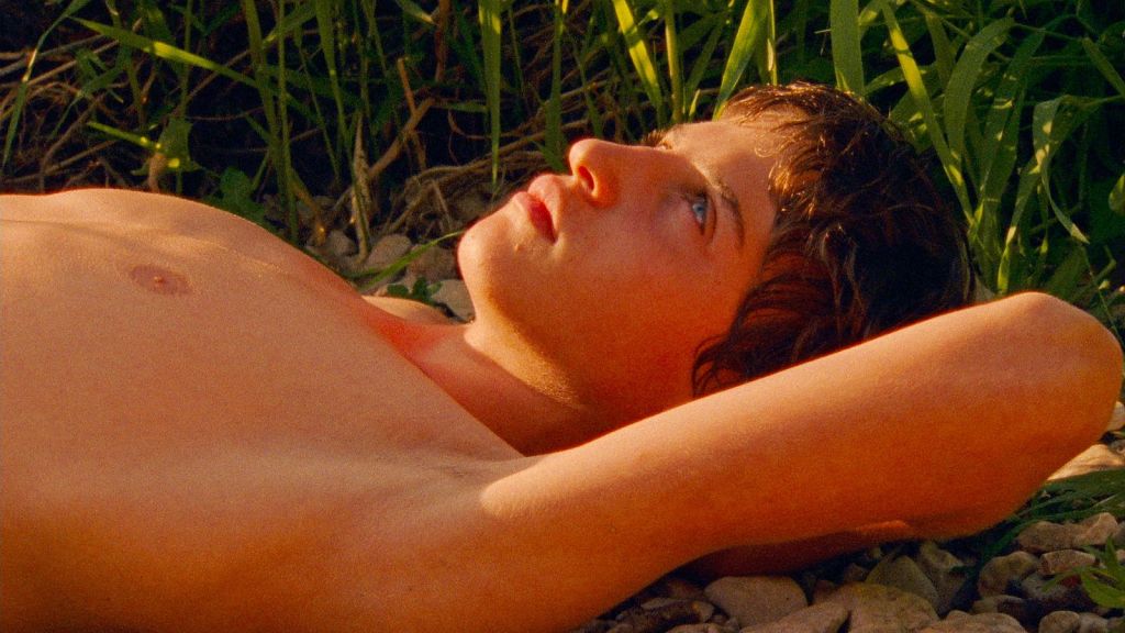 Fotograma de Extraño río mostrando la familia en bicicleta atravesando un bosque en verano.