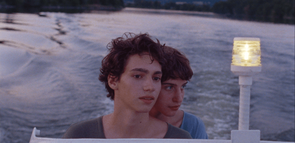 Plano de los protagonistas Dídac y Alexander compartiendo una mirada cerca del agua.