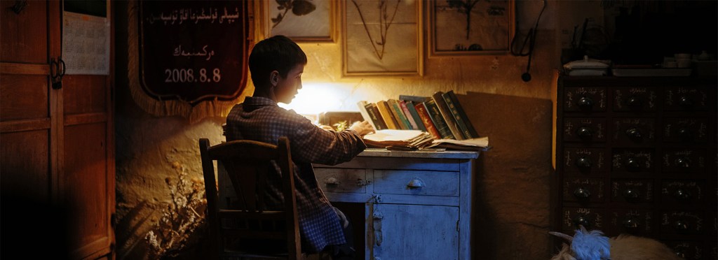 Plano de The Botanist (Jing Yi, 2025). Arsin, joven kazajo, escribe mientras la cámara destaca el espacio negativo del paisaje.